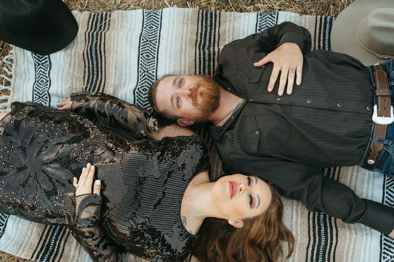 Engaged couple lying head to head on a striped blanket